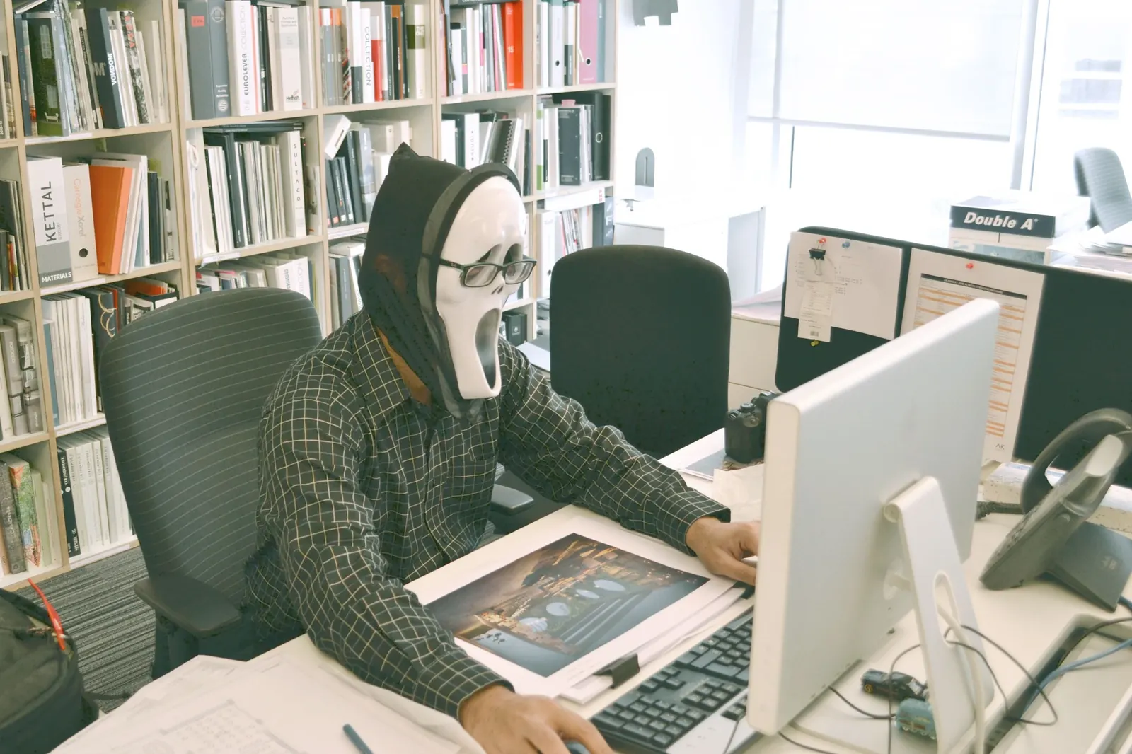 Person in a ghost mask working at an office computer